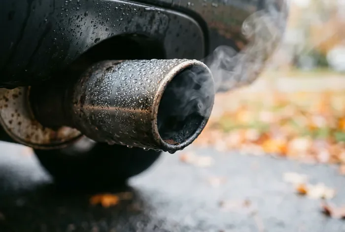Gros plan sur une sortie d'échappement de voiture avec de la fumée blanche