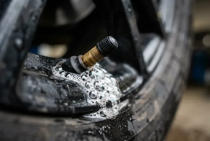 Pneu qui se dégonfle sans crevaison : 4 causes et solutions - Pneu qui se dégonfle sans crevaison : Le Guide Ultime (2026) - Pneu qui se dégonfle sans crevaison : Comment le réparer ? Gros plan sur une valve de pneu avec des bulles de savon
